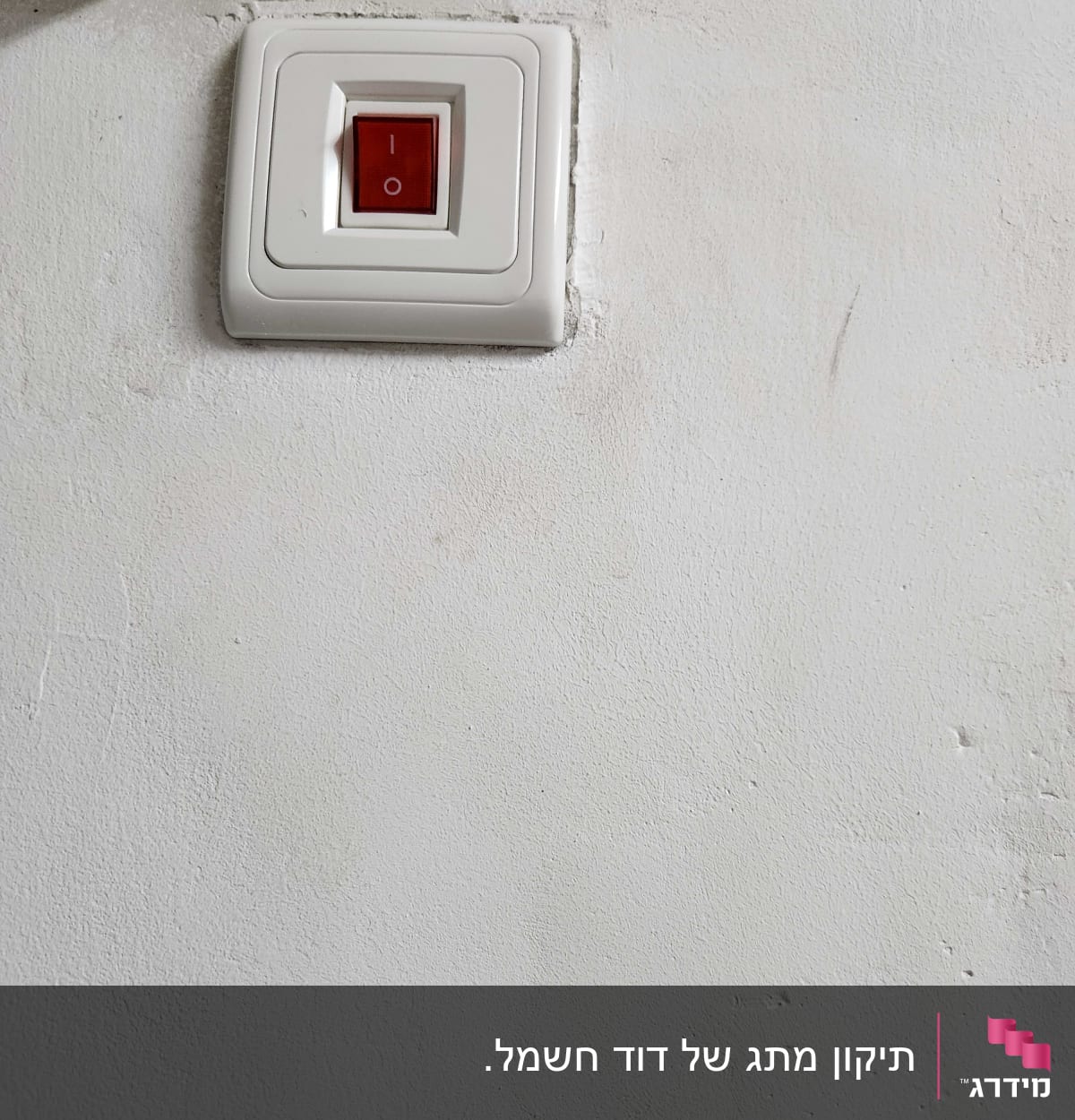 מתג חשמלי עם כפתור אדום על קיר לבן